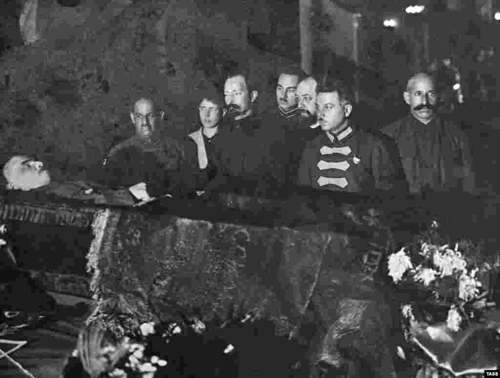 Большевистские начальники, в том числе Феликс Дзержинский (третий слева), печально известный основатель советской тайной полиции, организовавший множество массовых убийств, смотрят на тело Ленина. Конец января 1924 года. После смерти Ленина разгорелись дискуссии о том, что делать с его телом. Иосиф Сталин настаивал на том, чтобы труп забальзамировали и выставили на всеобщее обозрение, заявив, что это &laquo;не будет противоречить старым русским обычаям&raquo;. Лев Троцкий, ещё один лидер большевиков, отверг идею сделать из тела революционера-безбожника реликвию. Сохранение трупа для публичного поклонения не имеет &laquo;ничего общего с марксизмом&raquo;, возражал он