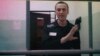 Russian opposition leader Alexei Navalny, seen on a TV screen as he appears in a video link, attends a hearing at the Russian Supreme Court in Moscow on August 23.