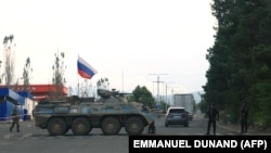 Azerbaijani police patrol next to a Russian peacekeepers' vehicle at a checkpoint along the road leading to the city of Xankendi/Stepanakert, Nagorno-Karabakh, on October 2.