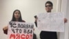 Студенты Карагоз Касым и Айсултан Кудайберген в международном аэропорту Алматы с плакатами для проведения акции против массового приезда россиян. 23 сентября 2022 года 