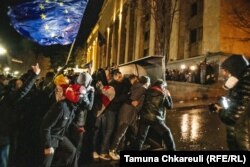 Протестующие движутся в сторону полицейского спецназа, прикрываясь щитом