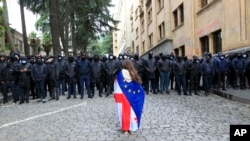 Demonstrantica ogrnuta gruzijskom i zastavom EU stoji ispred policijskog kordona na protestu opozicije u Tbilisiju (fotoarhiv)