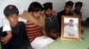 Mujtaba Hasan (second from left) with a picture of his brother of Atizaz, who reportedly sacrificed his life to stop a suicide bomber outside his school. 
