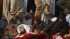 Children sit beside the body of one of the victims during a protest in front of the government offices in Peshawar.