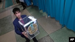 Сотрудник избирательной комиссии несет урну для подсчета бюллетеней на избирательном участке во время президентских выборов в Нур-Султане, 9 июня 2019 года.