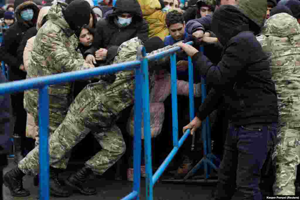 Білоруські військовослужбовці створили заслін, доки мігранти штовхаються, щоб отримати їжу. Захід звинуватив Лукашенка в &laquo;озброєнні міграції&raquo;, привозячи потенційних мігрантів до Білорусі та заохочуючи їх спробувати перетнути кордон із Польщею. Білорусь відкинула звинувачення та розкритикувала ЄС за відмову прийняти мігрантів