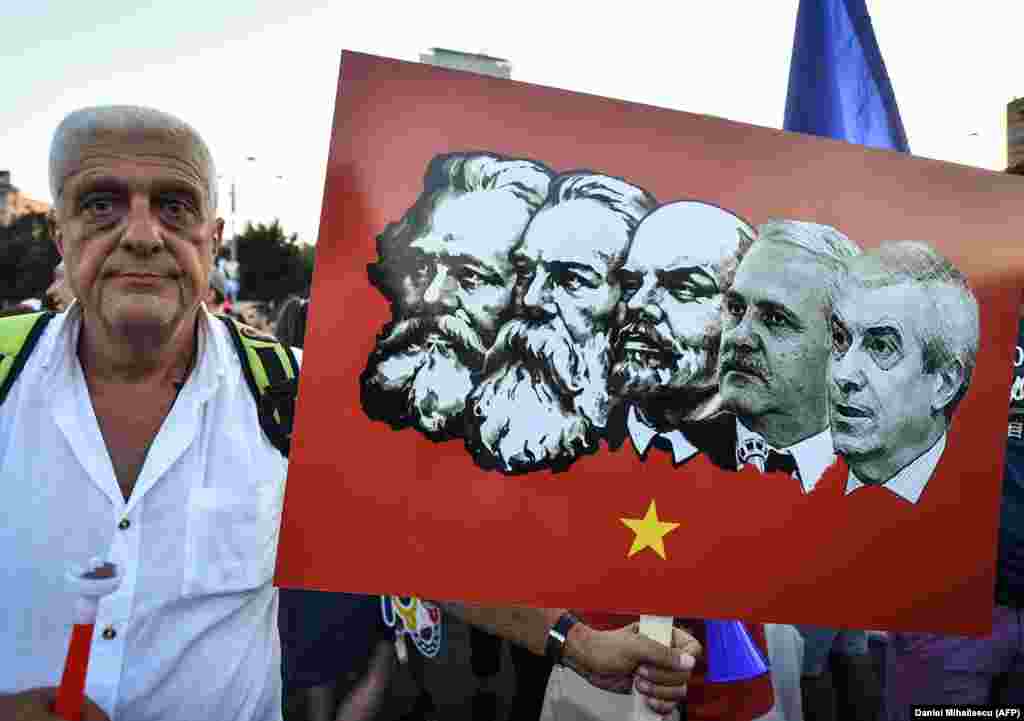 Протестувальник тримає плакат, на якому лідери лівої&nbsp;соціально-демократичної партії Румунії зображені разом&nbsp;з лідерами комунізму