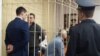 Падсудныя мытнікі Вадзім Лоха (стаіць у клетцы), Аляксандар Красаўцаў (на блізкім пляне) і Ўладзіслаў Гамолка