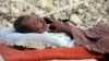 A survivor of the Balochistan earthquake sleeps near the rubble of his mud house. 