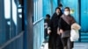 Iranian women wearing protective masks walk in Tehran.