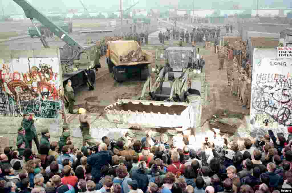 An East German bulldozer and crane knock down the Berlin Wall at Potsdamer Platz to make way for a new border crossing on November 12, 1989. Усходненямецкі бульдозэр і кран разьбіраюць Бэрлінскі мур каля Патсдамскай плошчы, каб зрабіць новы памежны пераход, 12 лістапада 1989.