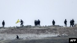 Боец курдских Отрядов народной самообороны (YPG) держит флаг своего движения на границе между Турцией и Сирией в Акчакале в провинции Шанлыурфа на 15 июня 2015Курдской Народной защиты подразделений ( YPG ) боец держит флаг своего движения возле пересечений ворот Акчакале между Турцией и Сирией в Акчакале в провинции Шанлыурфа, 15 июня 2015