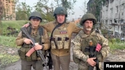 Wagner chief Yevgeny Prigozhin poses with two of his mercenaries as he makes a statement about withdrawing his forces from the embattled Ukrainian city of Bakhmut on May 25. 