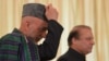 Visiting Afghan President Hamid Karzai (left) is flanked by Pakistani Prime Minister Nawaz Sharif as he adjusts his cap in Islamabad on August 26.